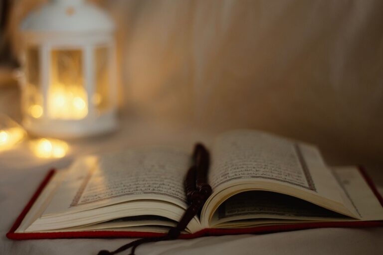The Art of Drawing Readers In: Your attractive post title goes here An open Quran with a decorative lantern softly lit in the background, symbolizing spirituality.